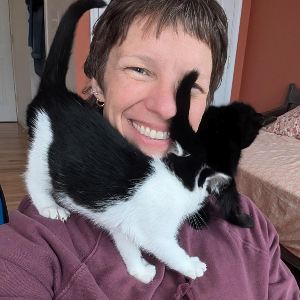 Foster parent with black and white kittens on shoulder