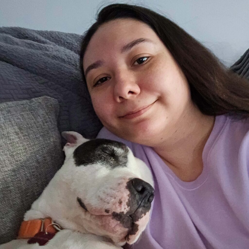 Woman in pink shirt cuddling with pitfall on the couch