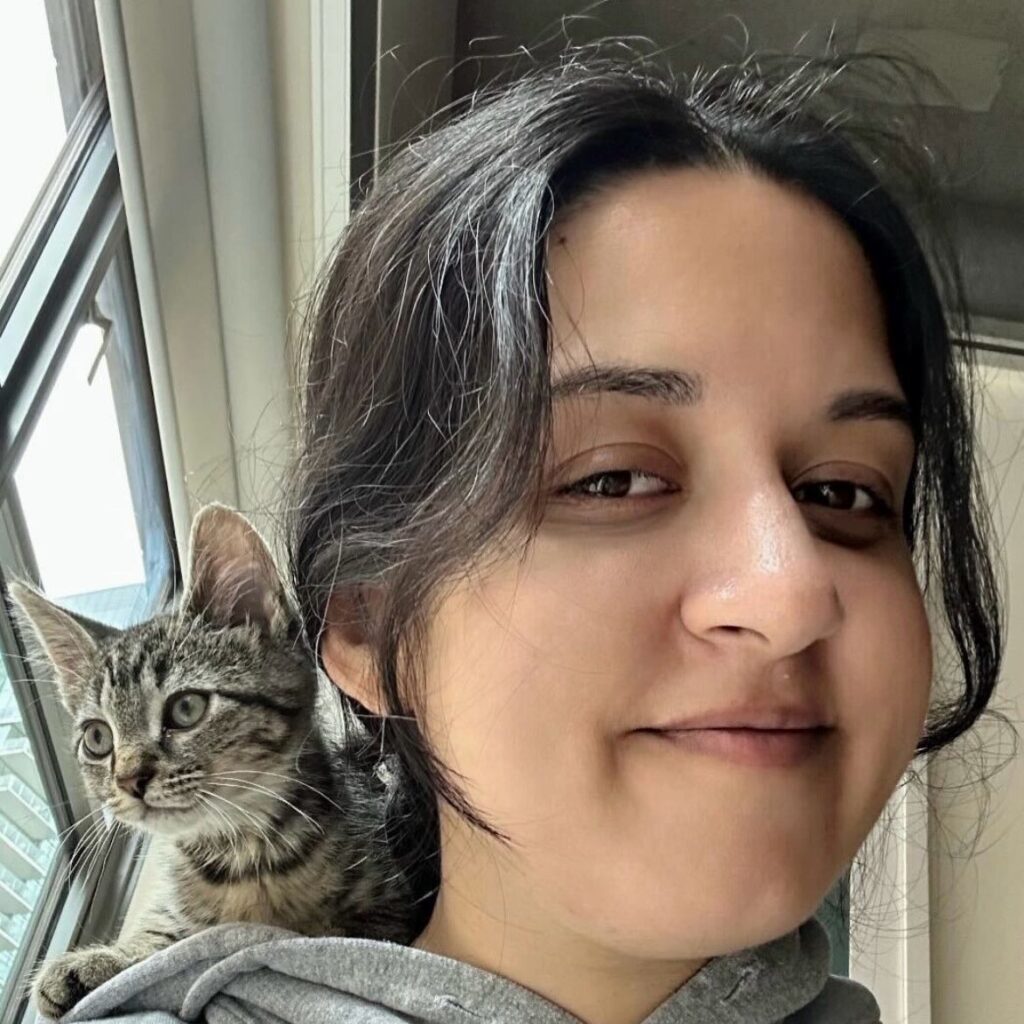 Woman in gray hoodie with cat on shoulder